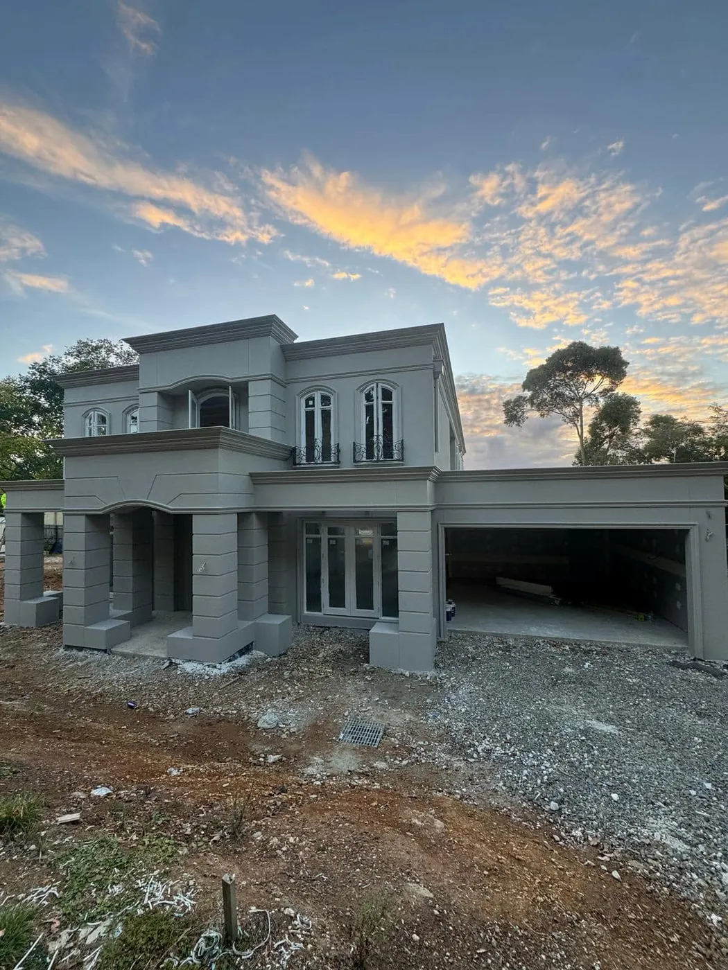 French provincial home with double garage at sunset, rendered in light grey