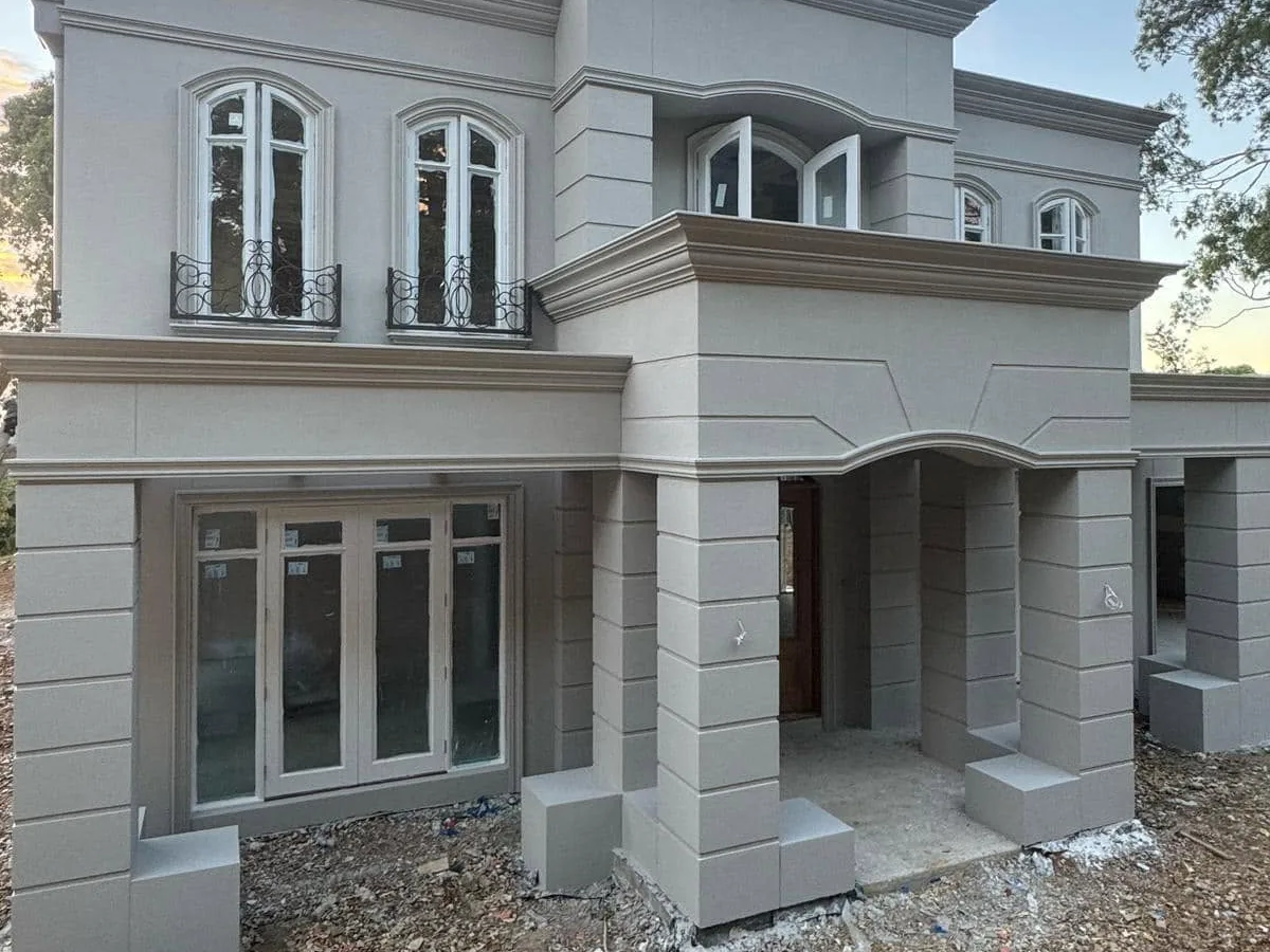 Arched windows with mouldings and Juliet balconies on a rendered French provincial facade