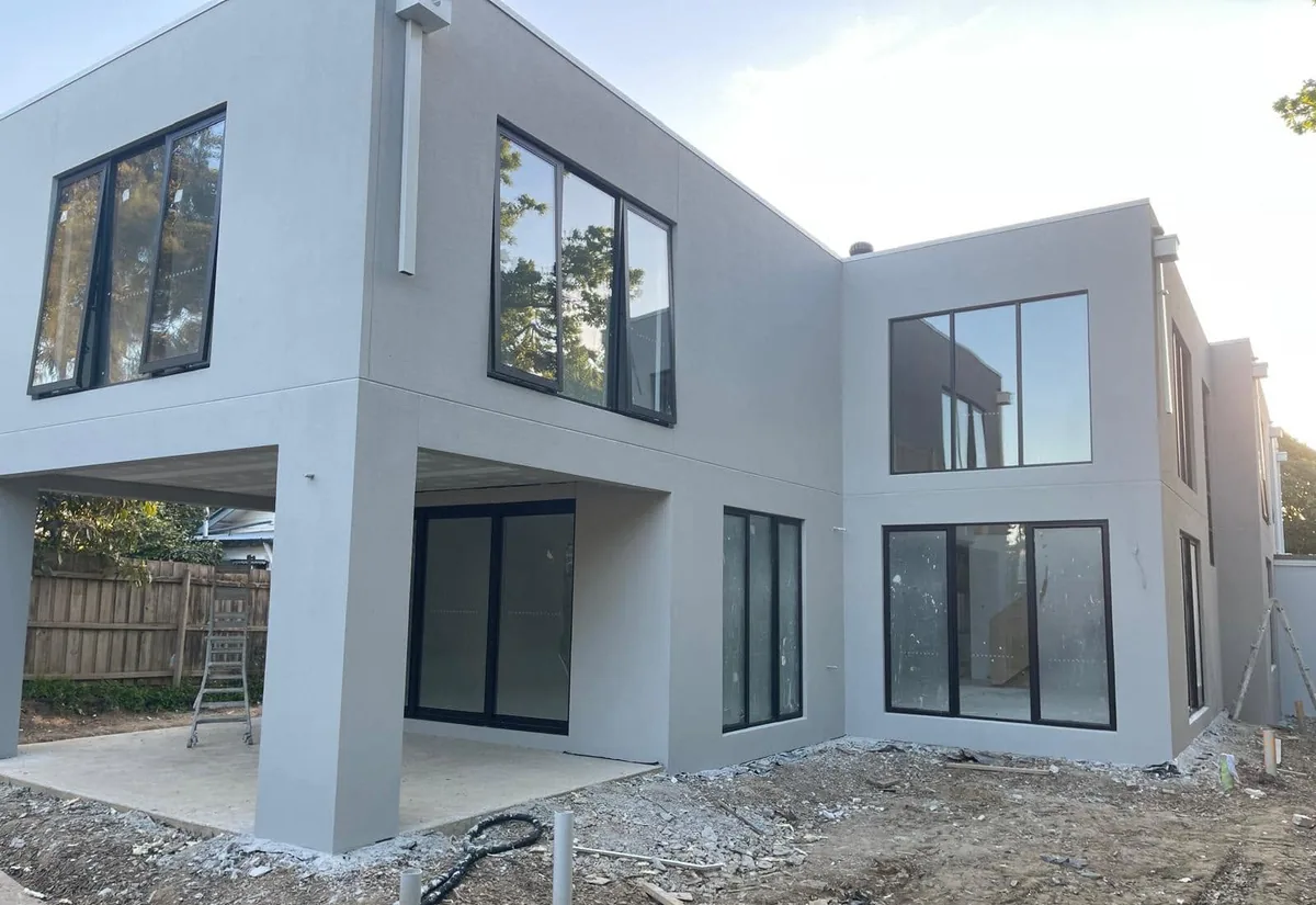 Modern rendered home with large black-framed windows